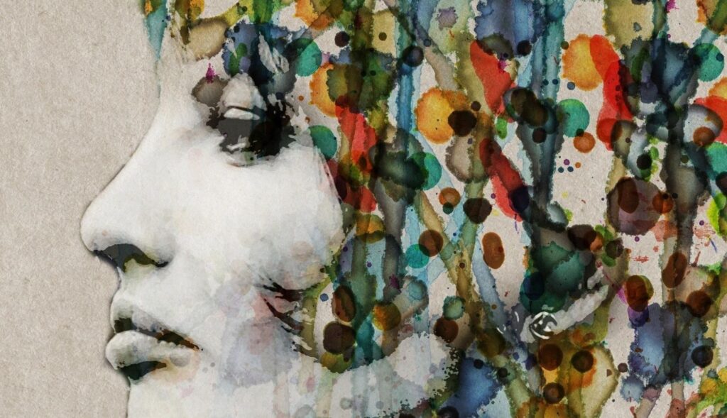 A woman 's face with colorful paint splashing all over her.