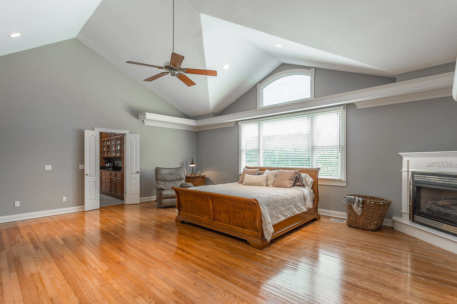 A bedroom with hard wood floors and vaulted ceilings.