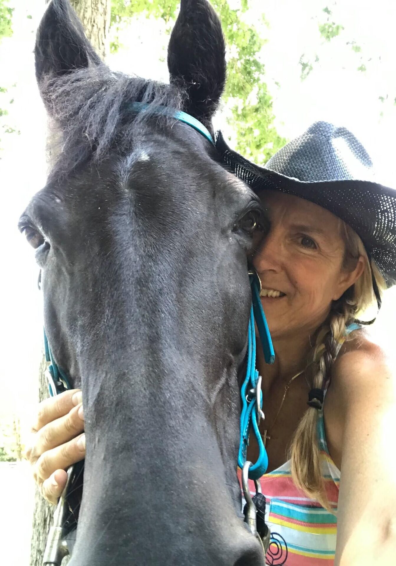 Tricia Peddicord A woman in a cowboy hat is petting the face of a horse.