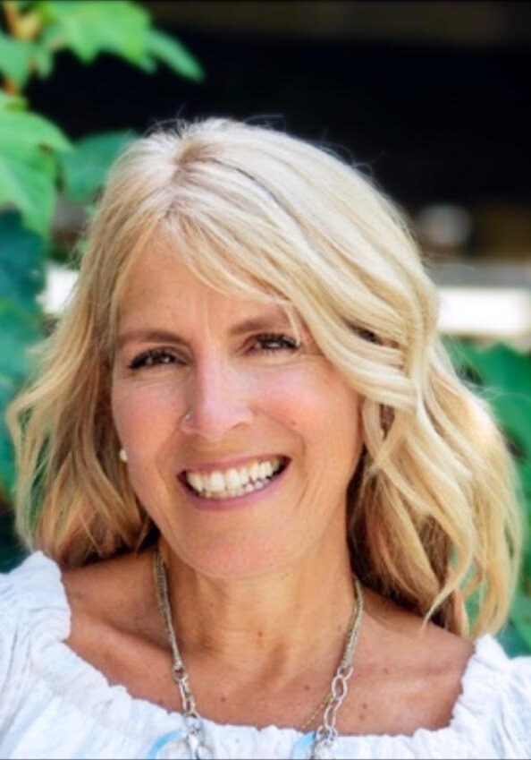 Tricia A woman with blonde hair and white shirt smiling.