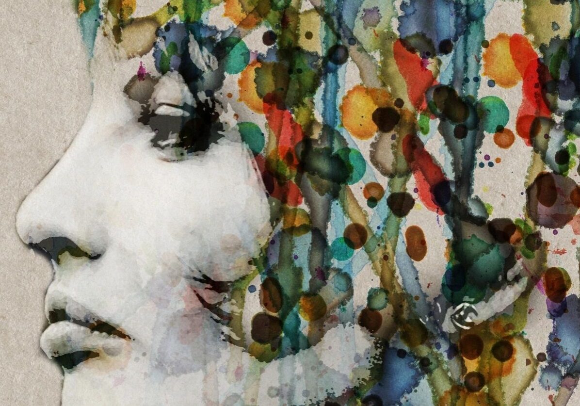 A woman 's face with colorful paint splashing all over her.